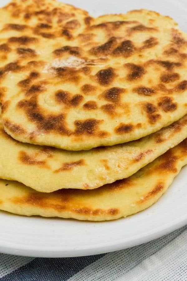 Instant Pot naan bread stacked on a white plate