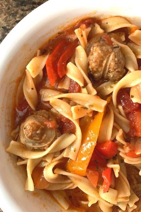Instant Pot sausage and peppers over pasta in a white bowl