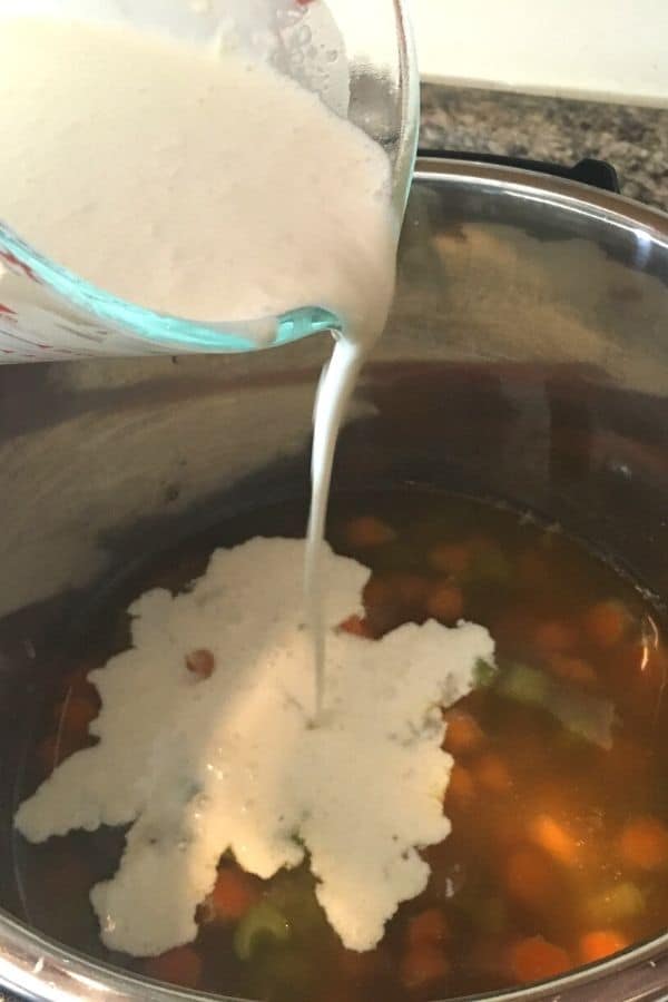 Flour and cream slurry being added to the Instant Pot to make chicken pot pie filling.