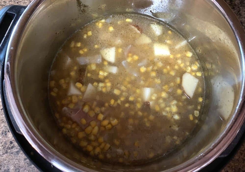 chicken, corn, potatoes, seasonings, and broth in the insert pot of the Instant Pot for making chowder