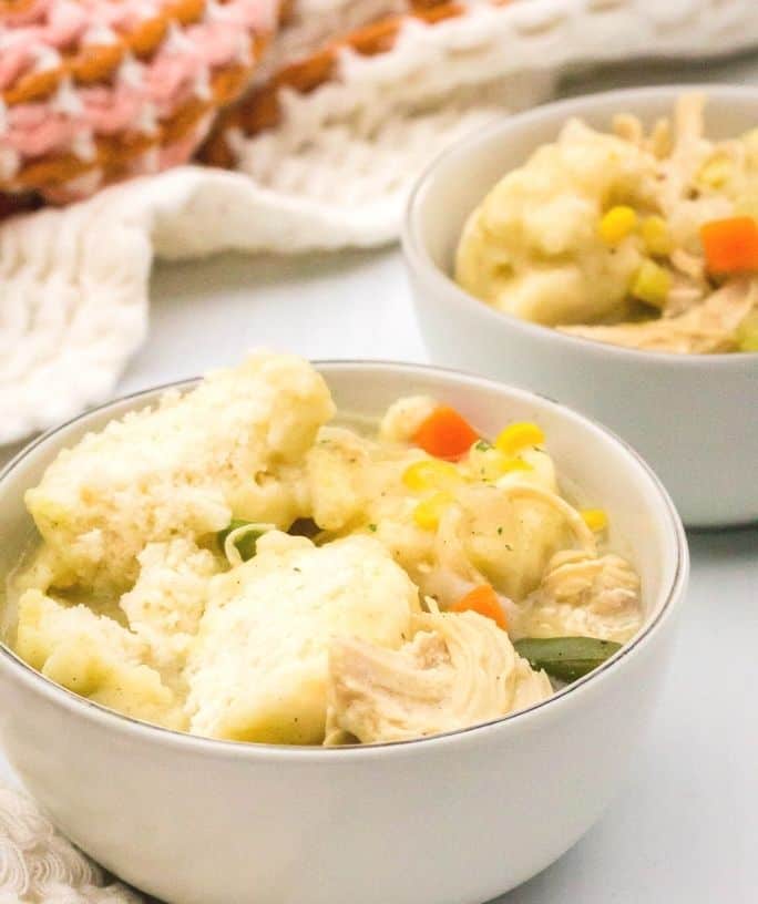 two white bowls filled with chicken and Jiffy mix dumplings