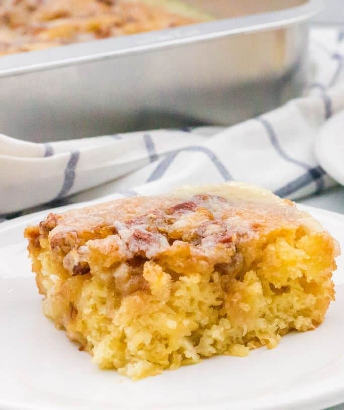 slice of granny cake on a white plate, next to the whole pan of cake