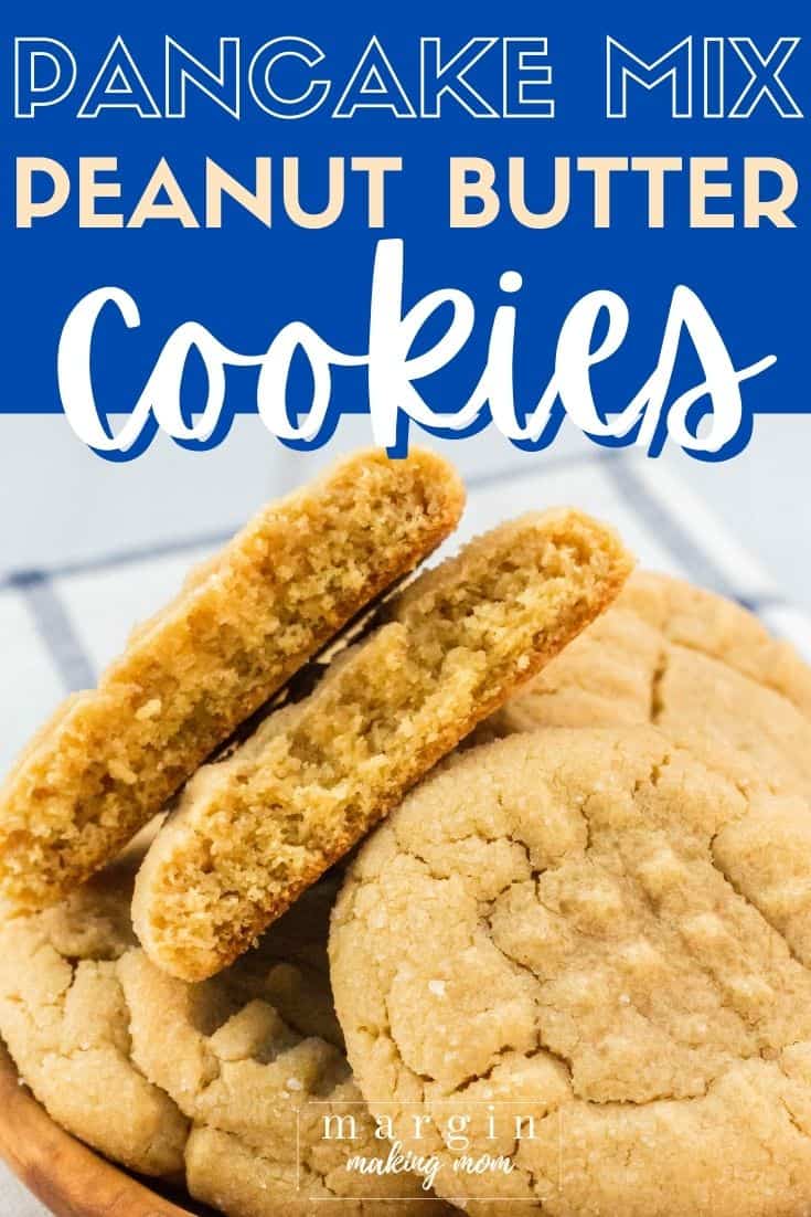 a few pancake mix peanut butter cookies on a small wooden plate, with one cookie broken in half to show the soft interior.