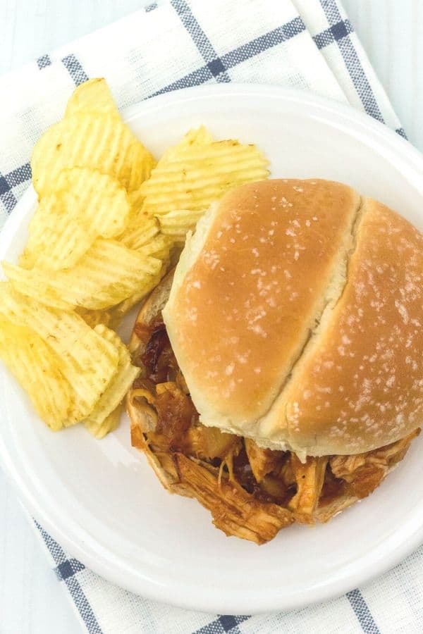 aerial view of a Hawaiian BBQ pulled chicken sandwich on a white plate with some potato chips