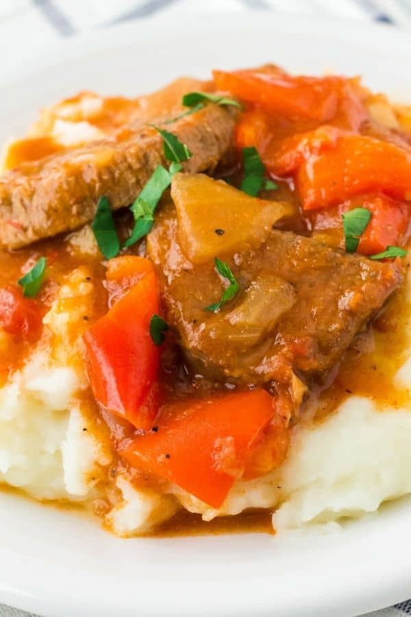 close-up view of mashed potatoes and Instant Pot Swiss Steak, topped with chopped fresh parsley and served on a white plate