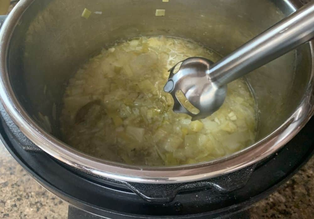 Instant Pot potato leek soup freshly cooked, with an immersion blender about to puree the soup