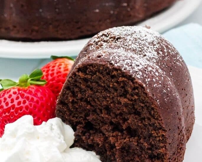 Slice of chocolate cake made with sour cream, served with strawberries and whipped cream