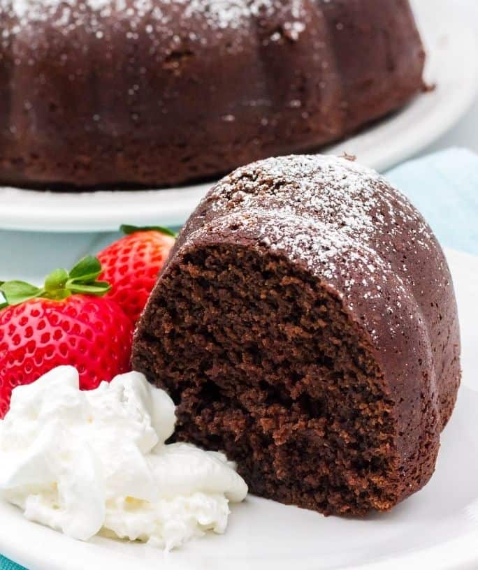 Slice of chocolate cake made with sour cream, served with strawberries and whipped cream