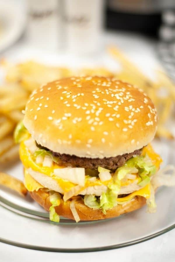 a double cheeseburger cooked in the Instant Pot served on a clear glass plate with a side of french fries