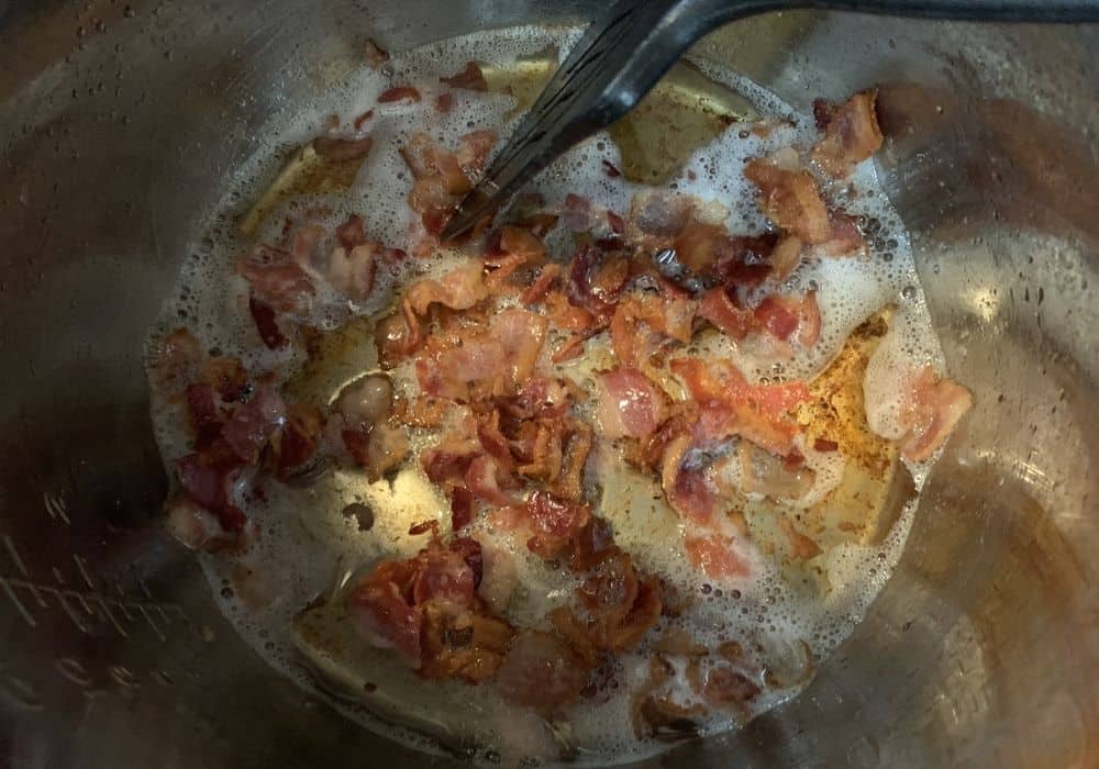 pieces of bacon being cooked in the insert pot of the Instant Pot.