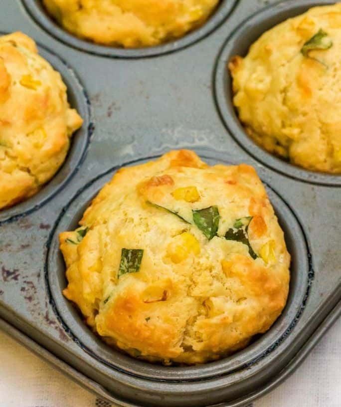 cheesy corn and basil muffins in a muffin pan