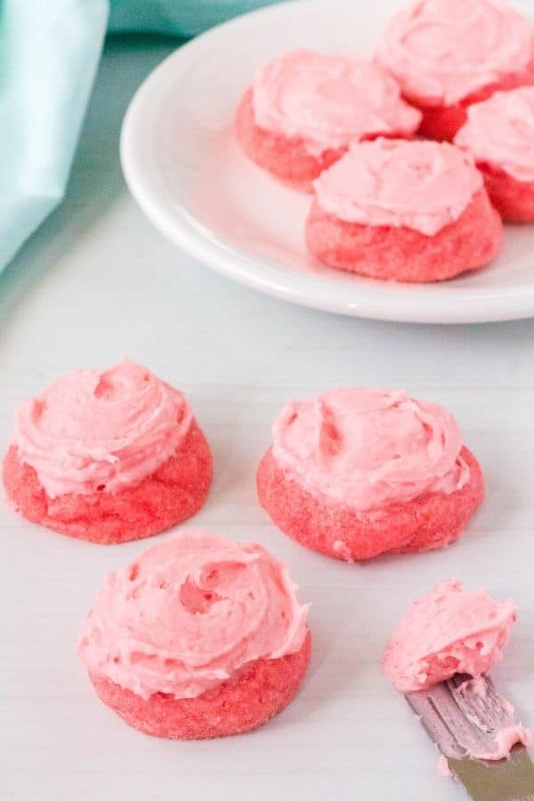 pink Jello sugar cookies with frosting, and a small frosting knife next to them