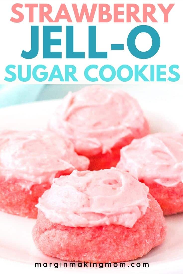 four strawberry jello cookies on a white plate, each topped with pink frosting