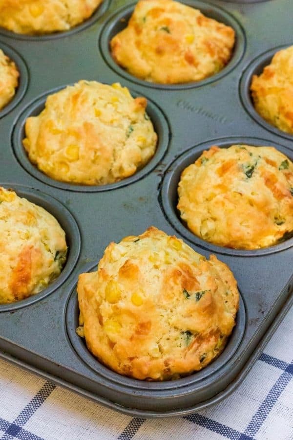 fresh cheesy corn muffins with basil hot out of the oven, still in the muffin pan