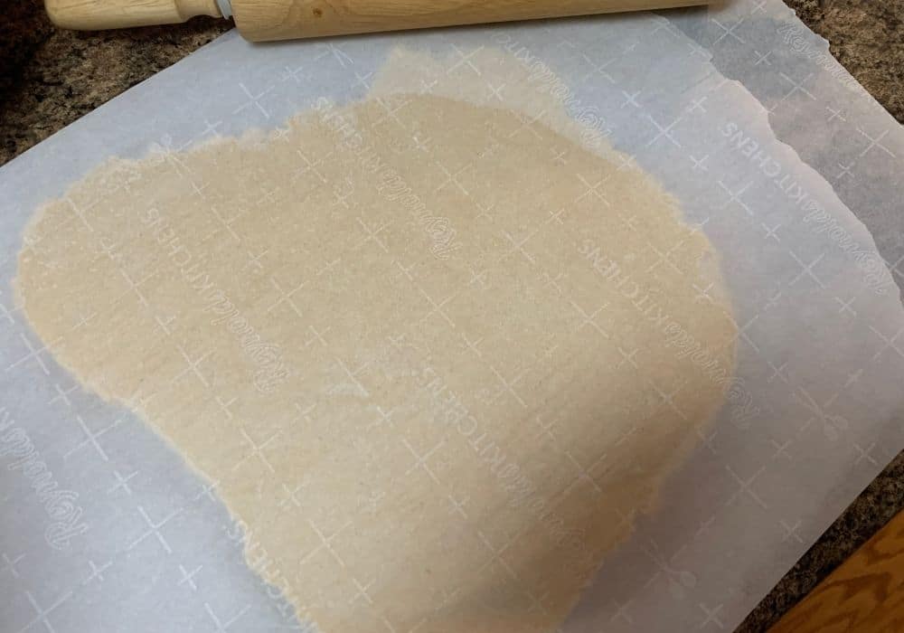 Italian sour cream cookie dough rolled out between two sheets of parchment paper