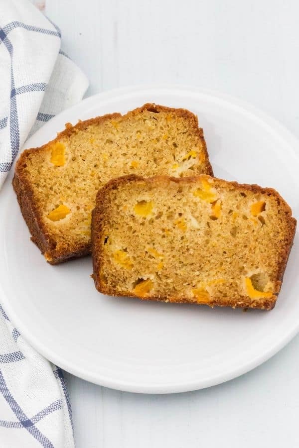 overhead view of two slices of peach bread on a white plate, next to a blue and white napkin