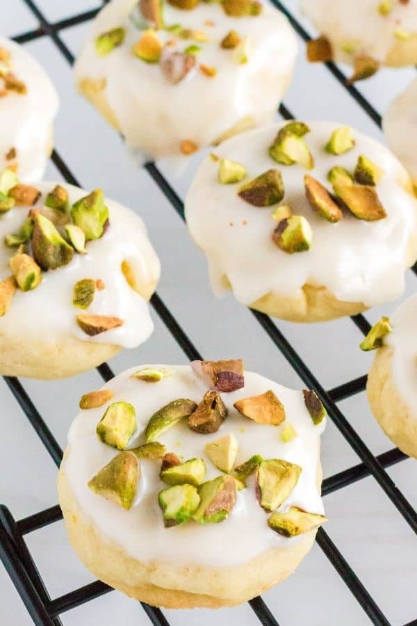 freshly iced lemon pistachio cookies on a cooling rack