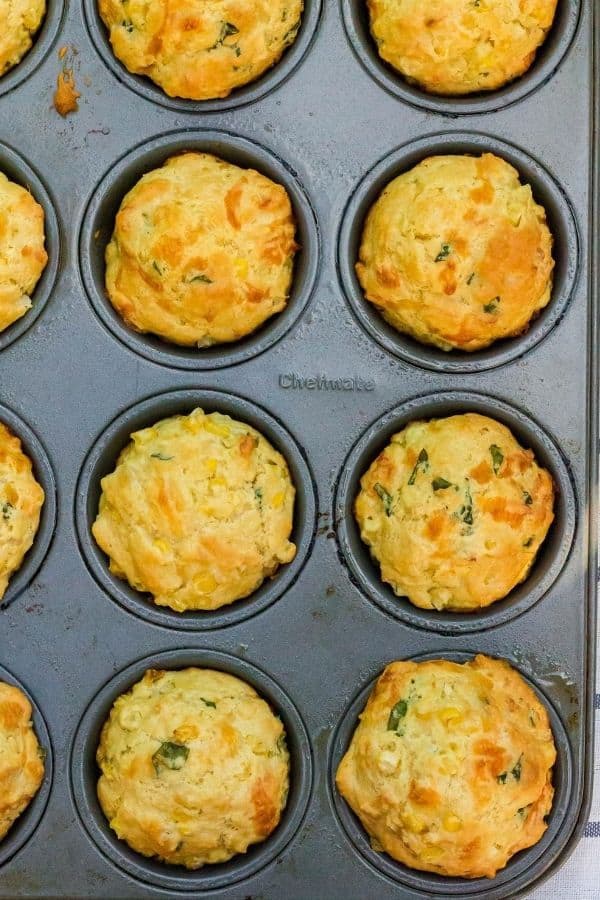 muffin pan filled with freshly baked cheesy corn and basil muffins