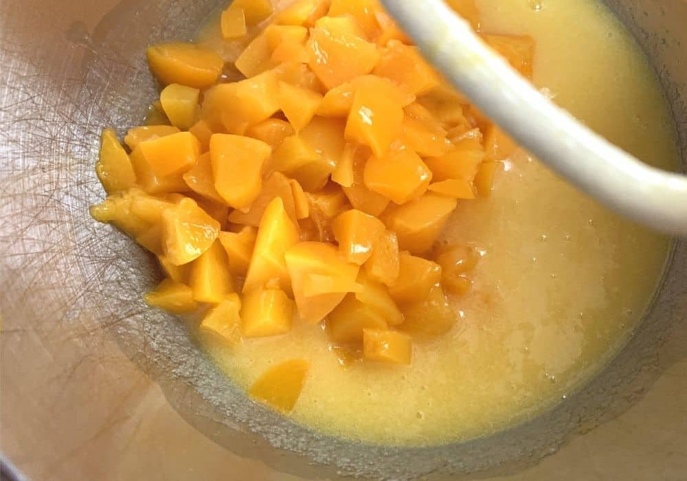Wet ingredients for peach bread batter in the bowl of a stand mixer