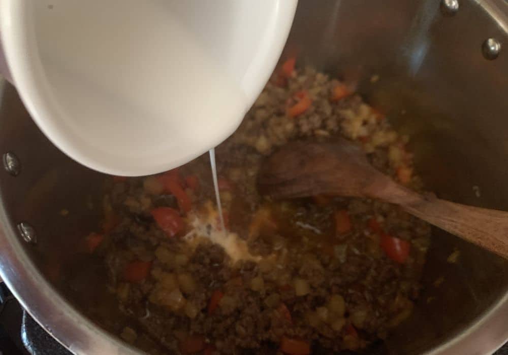 cornstarch slurry being added to the Hawaiian Sloppy Joe mixture in the Instant Pot to thicken the sauce.