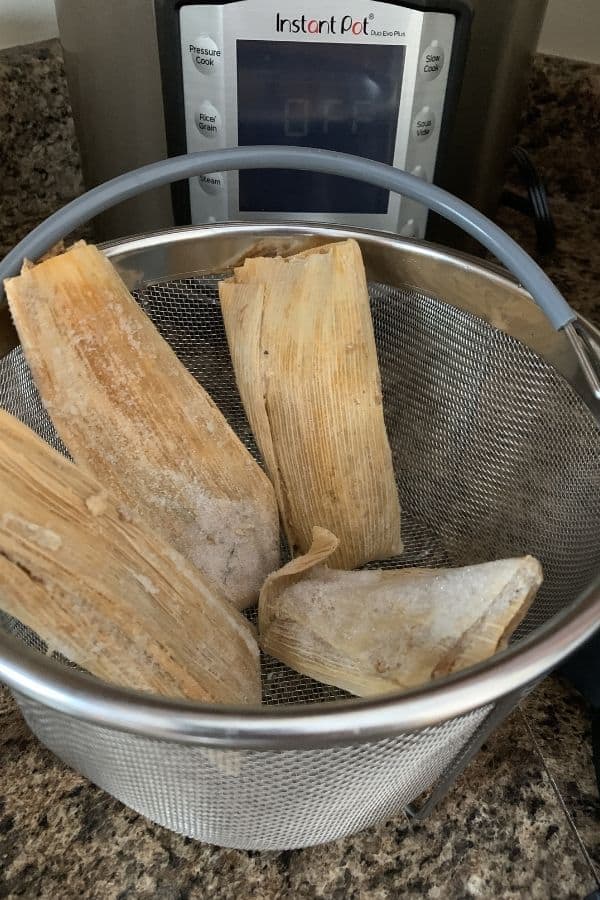 Four frozen tamales in a steamer basket, for reheating in the Instant Pot