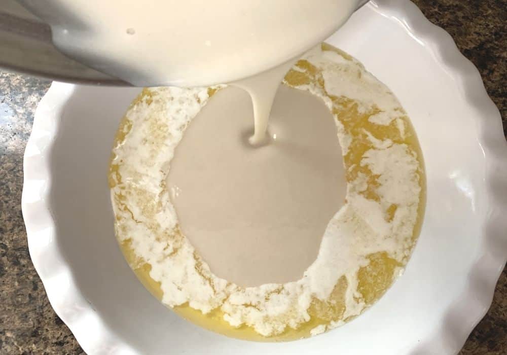 batter being poured into the melted butter in the pie pan