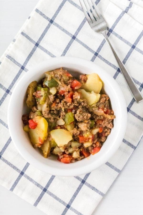 Instant Pot Dolly Parton casserole helping in a white bowl atop a blue and white checkered napkin