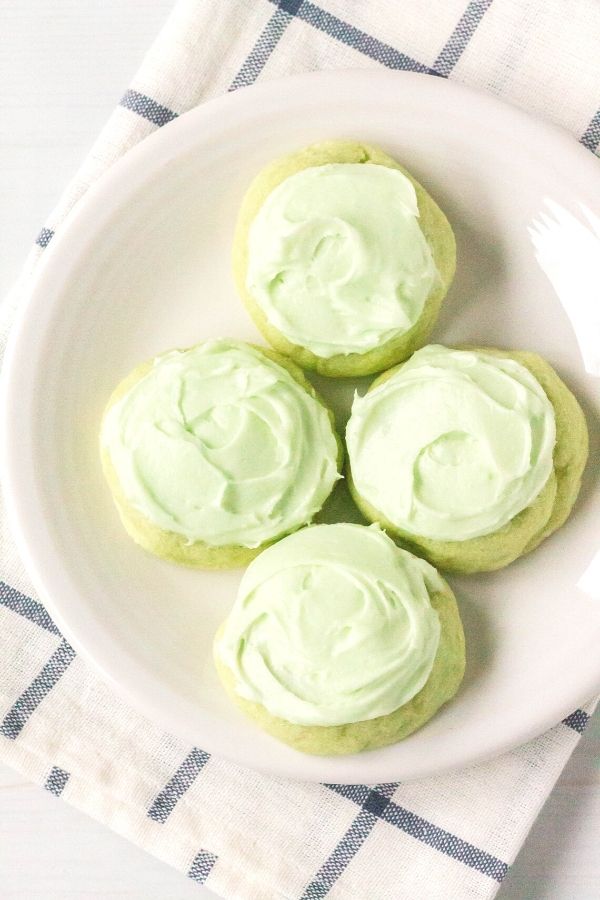 a white plate with lime jello sugar cookies topped with pale green icing