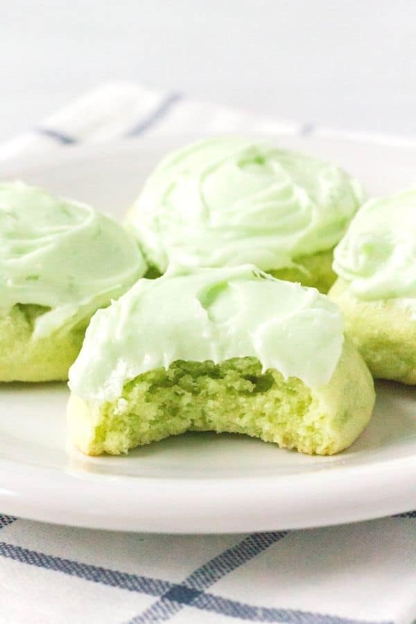 four lime jello cookies on a white plate, with a bite taken out of the front cookie