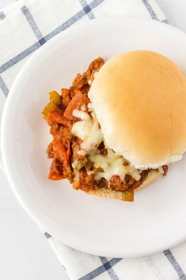 overhead view of an Instant Pot pizza guiseppe sandwich on a white plate atop a blue and white cloth napkin