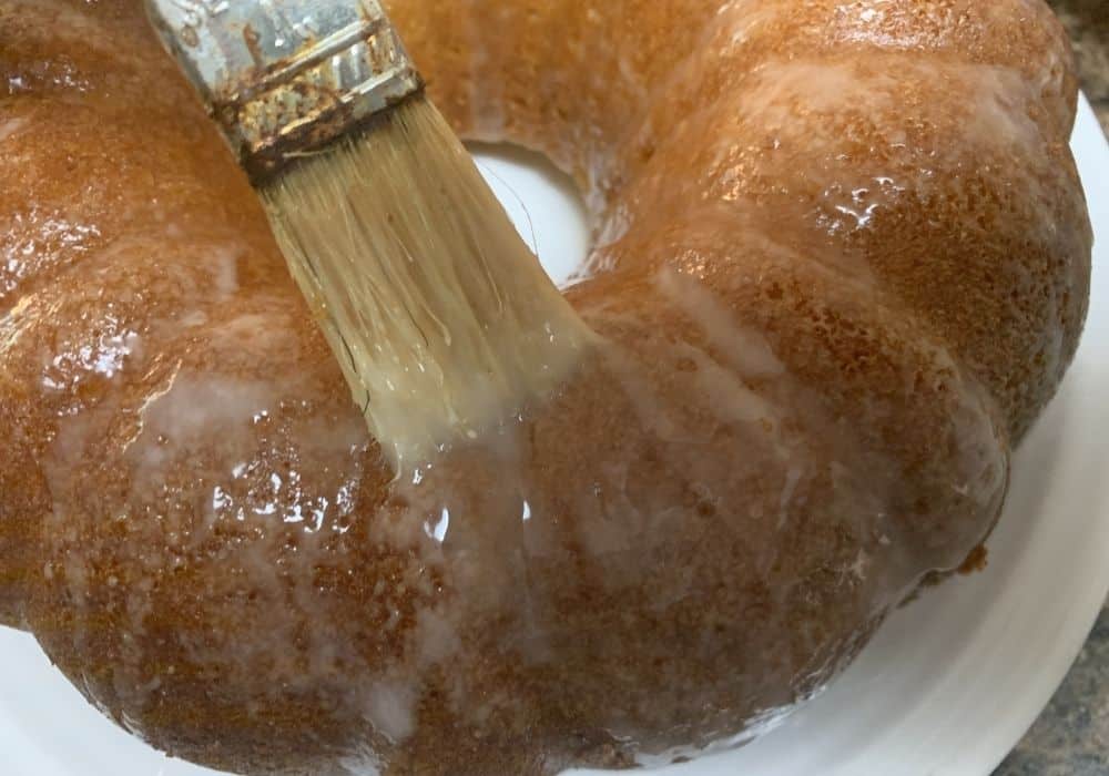 glaze being brushed onto the apricot nectar cake