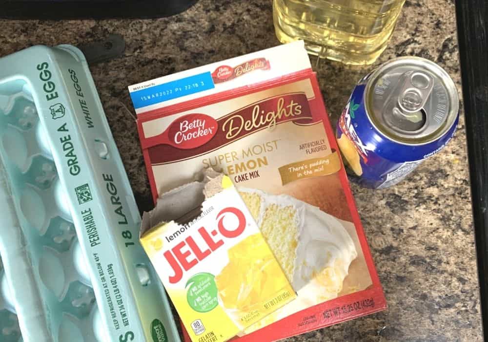 ingredients for the apricot nectar cake on a kitchen counter, including eggs, lemon jello, lemon cake mix, oil, and a can of jumex apricot nectar