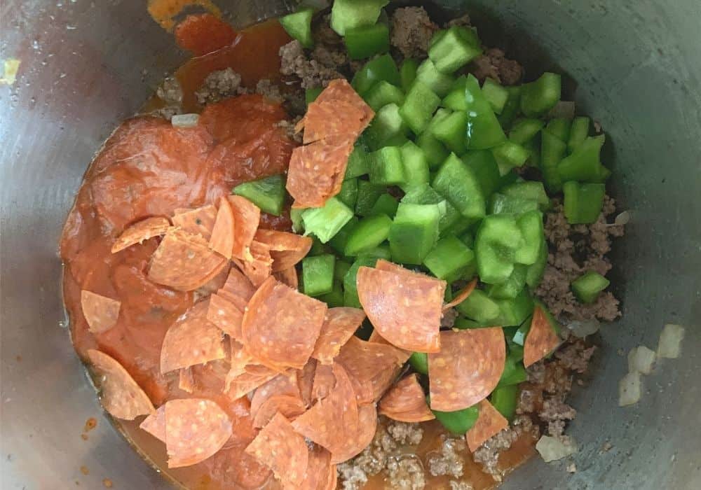 ingredients for instant pot pizza sloppy joes, including pizza sauce, pepperoni, green bell peppers, onions, and ground beef.