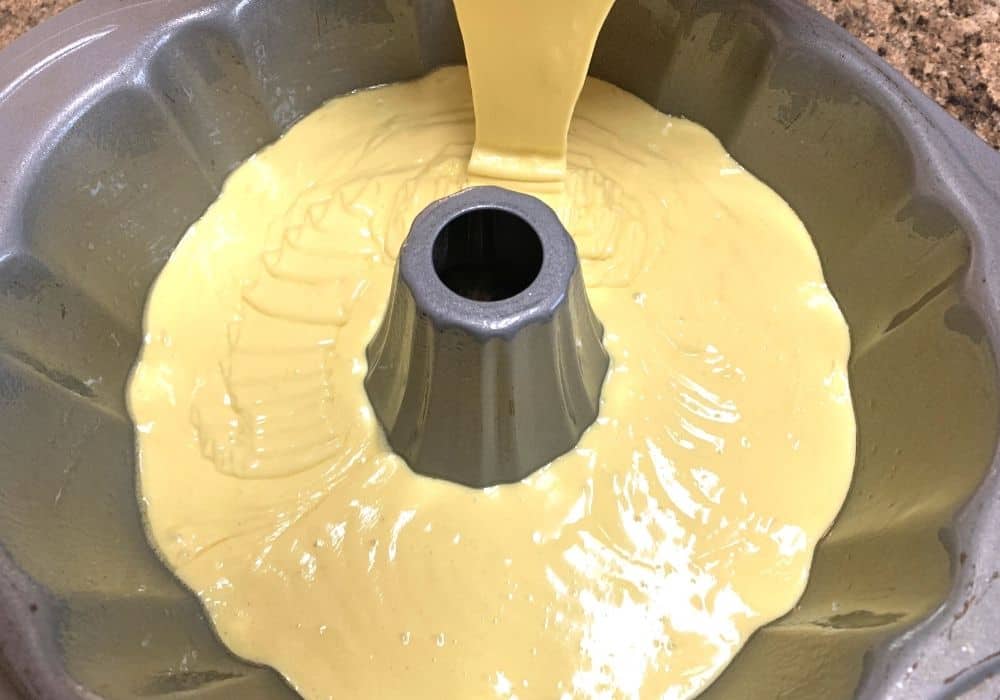 batter for a cake made with apricot nectar being poured into a prepared bundt pan