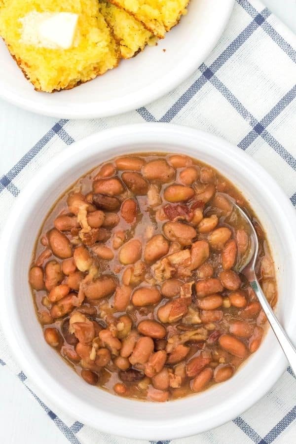 overhead view of a coal miner's dinner, including a white bowl of pinto beans cooked in the pressure cooker, plus a white plate of cornbread with butter.