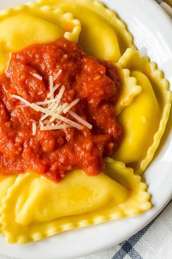 frozen ravioli cooked in the Instant Pot topped with sauce on a white plate