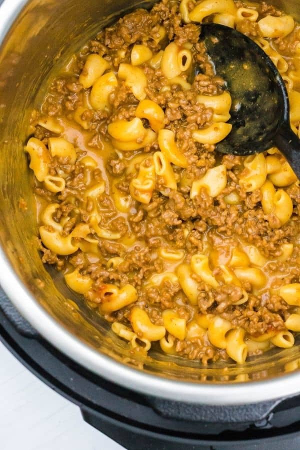 overhead view of the insert pot in the Instant Pot, with freshly cooked Hamburger Helper and a black serving spoon.