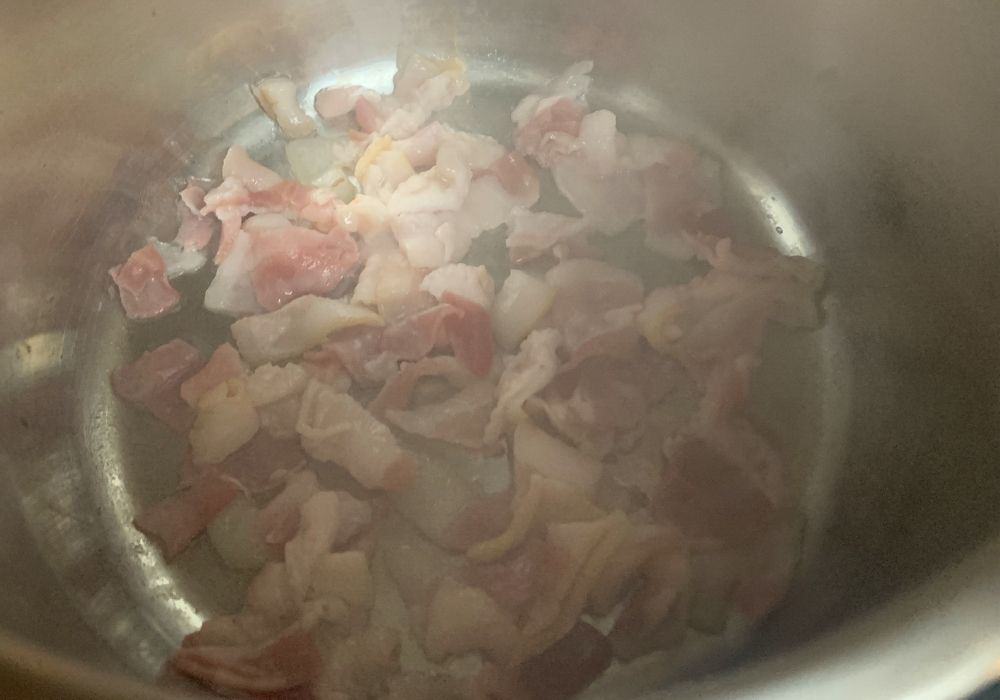 pieces of bacon being cooked until crisp in the Instant Pot for pinto beans