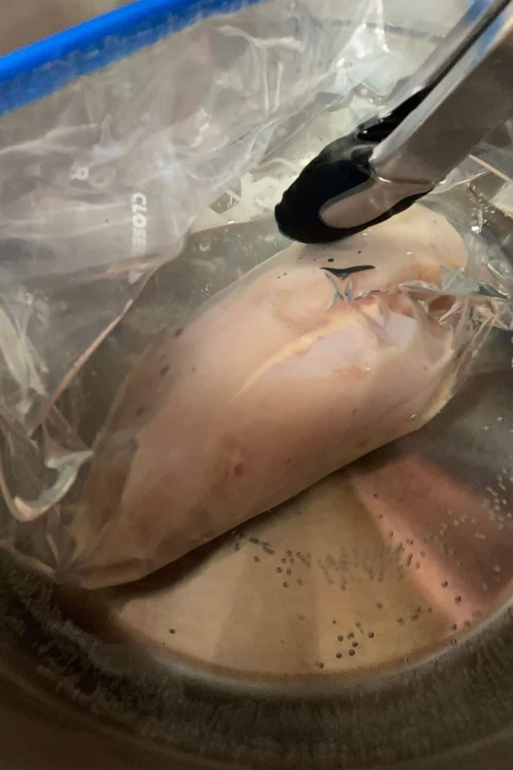 bag of chicken being lowered into the hot water bath of the instant pot