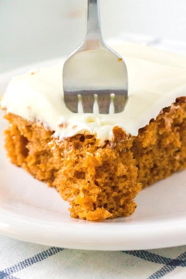 side view of the corner of a slice of tomato soup sheet cake, with a fork taking a bite out of the cake