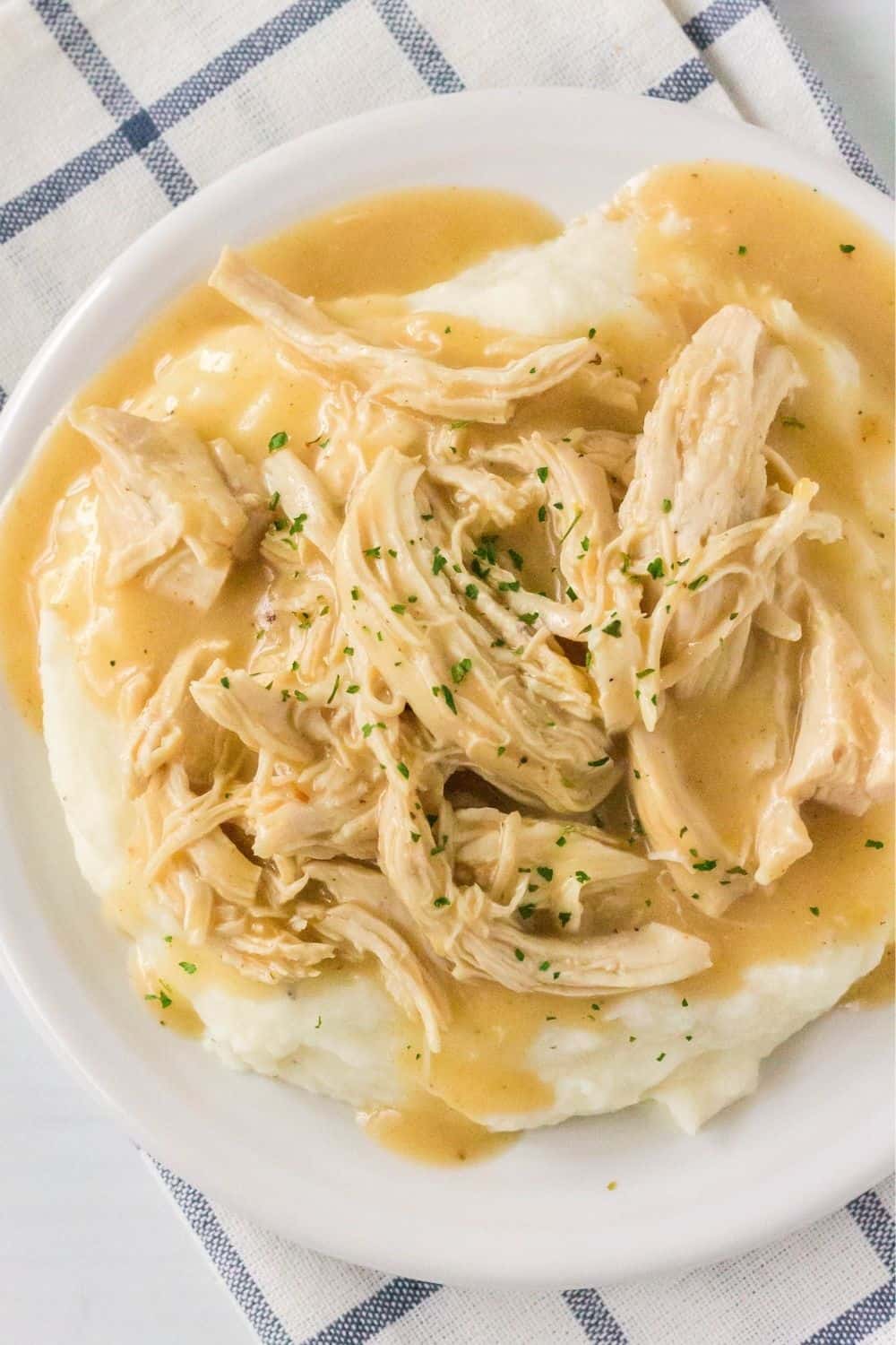 overhead view of a white plate with a serving of Instant Pot chicken and gravy over a bed of mashed potatoes