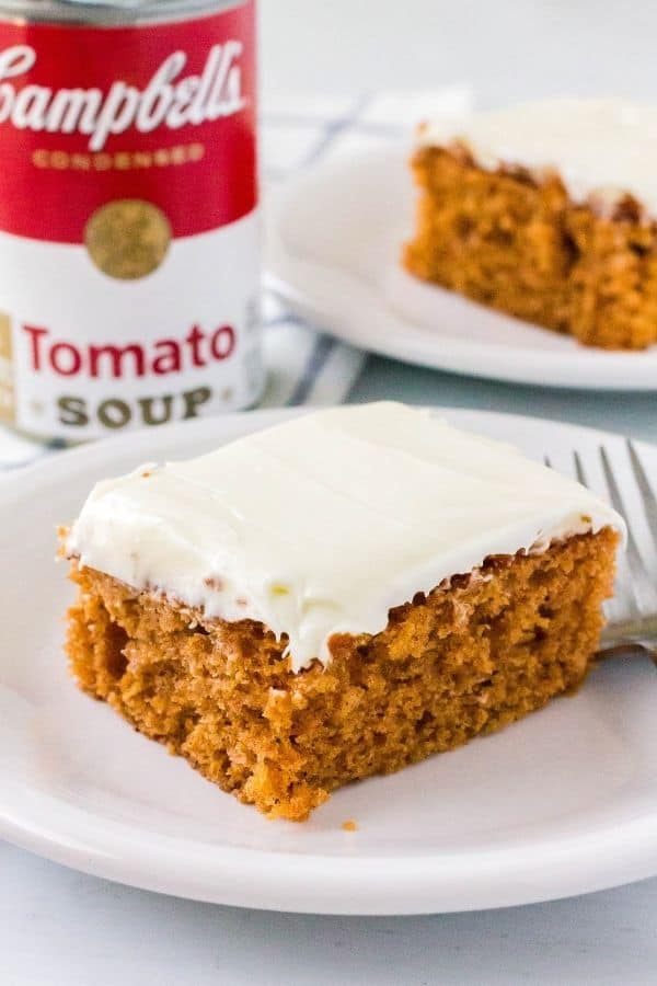 a slice of spice cake made with condensed tomato soup, topped with frosting, on a white plate