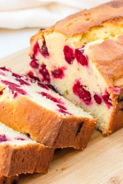 sliced loaf of cranberry cream cheese bread on a wooden cutting board
