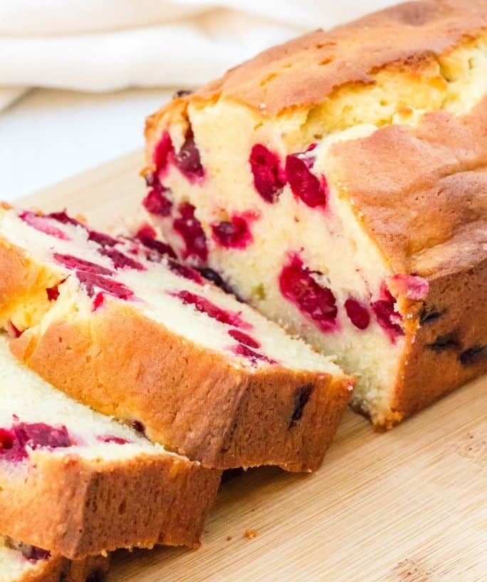 sliced loaf of cranberry cream cheese bread on a wooden cutting board