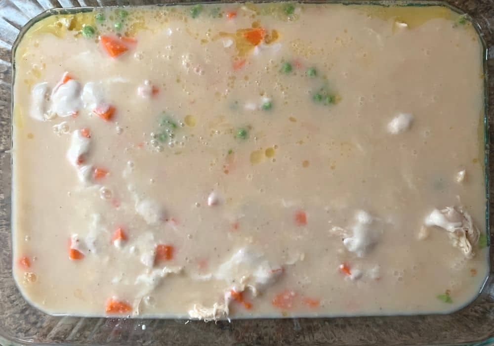 chicken and dumpling casserole ingredients in a baking dish ready to be placed in the oven