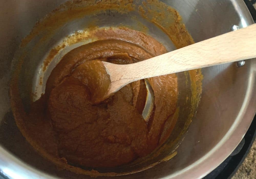 freshly cooked pumpkin butter in the Instant Pot, stirred with a wooden spoon