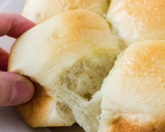 hand pulling apart Rhodes dinner rolls that rose from frozen in the Instant Pot