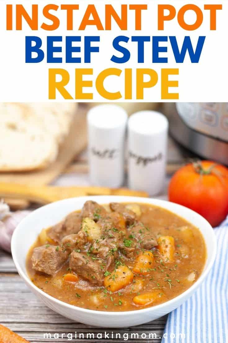 a white bowl of pressure cooker beef stew in front of salt and pepper and crusty bread