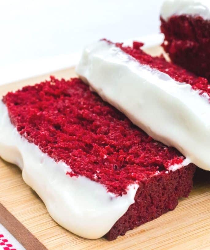 a slice of red velvet loaf cake on a cutting board
