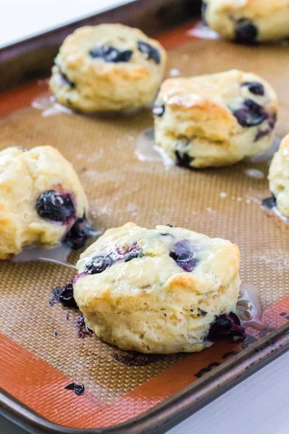 freshly glazed biscuits with blueberries on a baking sheet